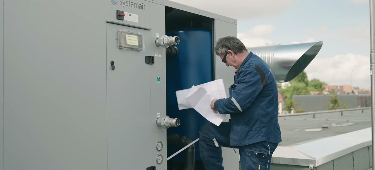 Standbild aus dem Firmenvideo: ein Monteur der DEGEN GmbH an einer Lüftungsanlage auf einem Dach